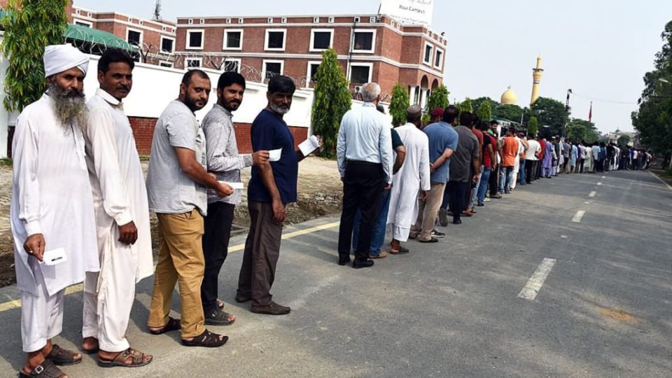 Voters stand in queue outside polling station in Johar Town, Lahore